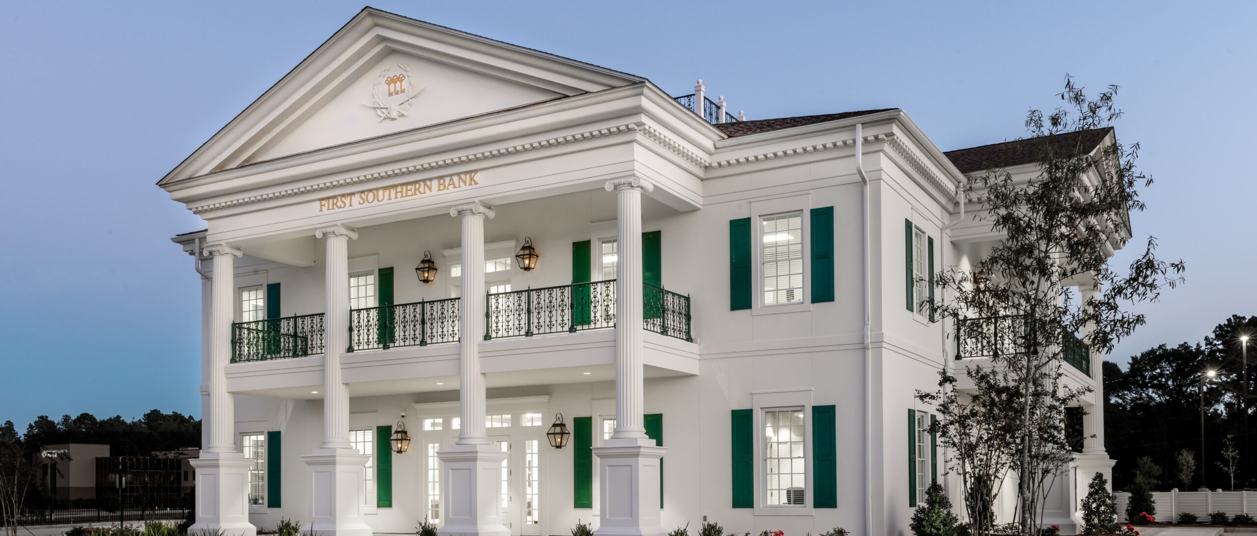 Exterior view of First Southern Bank showcasing neoclassical architecture with a prominent columned portico, symmetrical facade, decorative iron railings, and traditional architectural detailing.